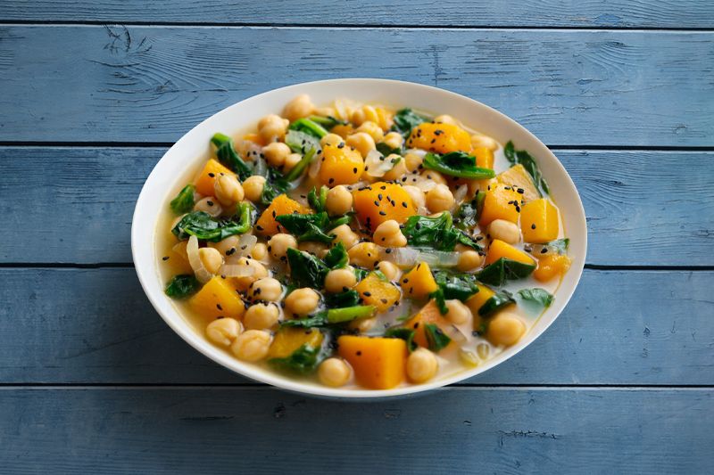 Cebolla dulce - Plato de garbanzos con espinacas y calabaza sobre una mesa de madera color azul