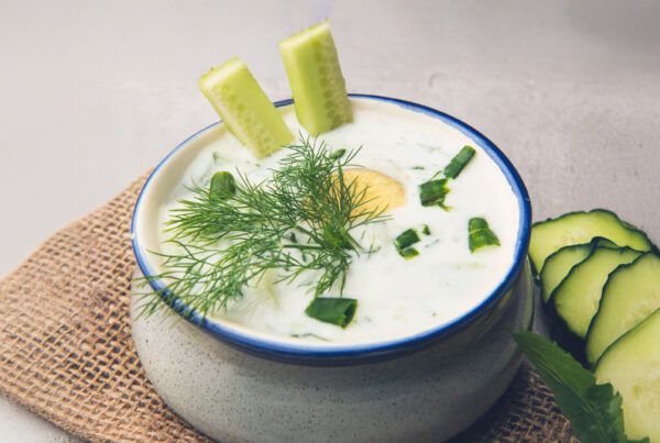 Bol de crema fría de pepino, yogur y eneldo sobre una esterilla.