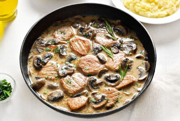 Plato negro metálico con lomo en salsa de cebolla dulce y champiñones