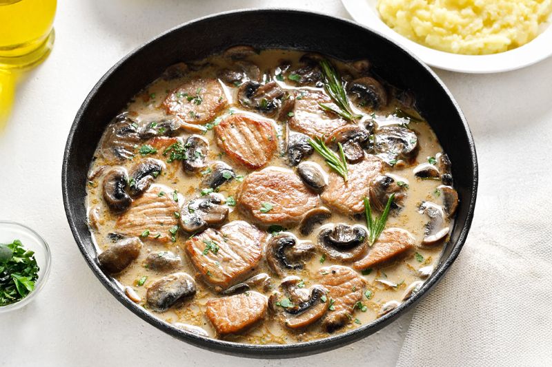 Plato negro metálico con lomo en salsa de cebolla dulce y champiñones