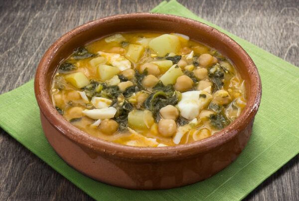 Cazuela de potaje de garbanzos sobre una servilleta verde en una mesa de madera