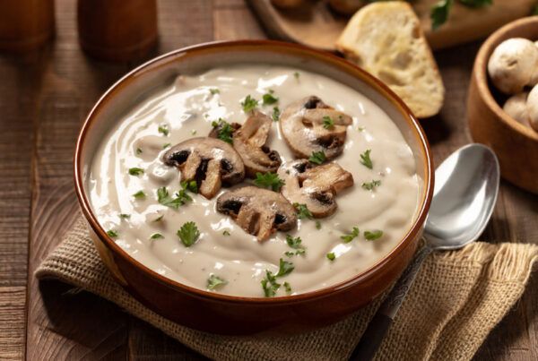 Plato de crema de champiñones sobre una servilleta de arpillera en una mesa de madera oscura.